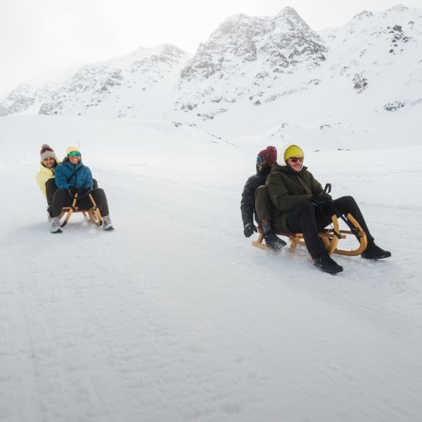 Trois personnes assises sur une luge dans la neige