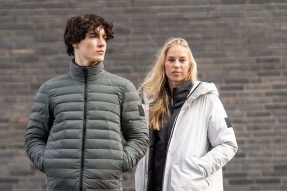 Une femme et un homme en vestes d'hiver décontractées devant un mur