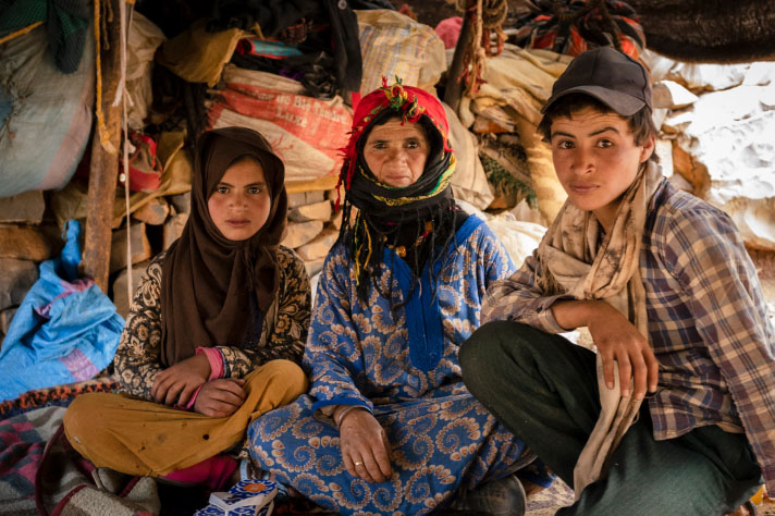 Une femme et deux enfants devant des sacs