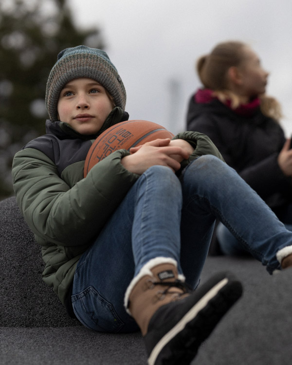 Garçon assis avec un ballon de basket dans ses bras