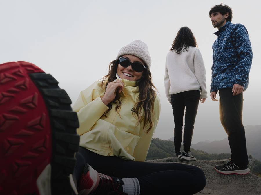 Trois jeunes adultes en vêtements outdoor sportifs se trouvent dans un paysage montagneux