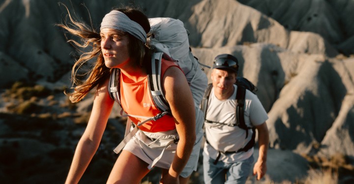 Une femme et un homme en tenue de randonnée estivale au coucher du soleil